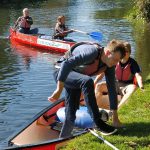 Alex disembarking from the canoe while James S holds it steady