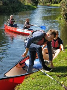 Alex disembarking from the canoe while James S holds it steady